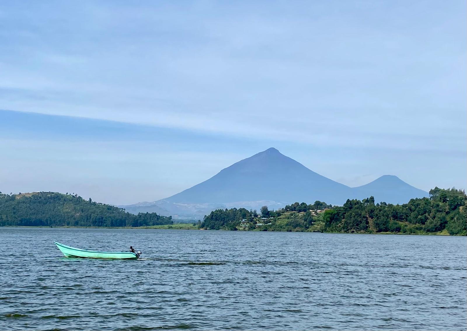 Boat crossing Lake Mulehe with the Virunga Volcanoes in the distance